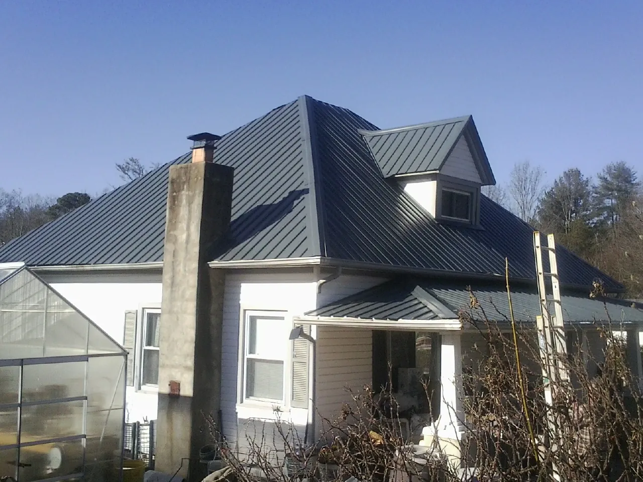 Dark blue standing seam metal roof on a white farmhouse with dormer — Slate & Tile Roof Repair by Roofing Brothers in Illinois City