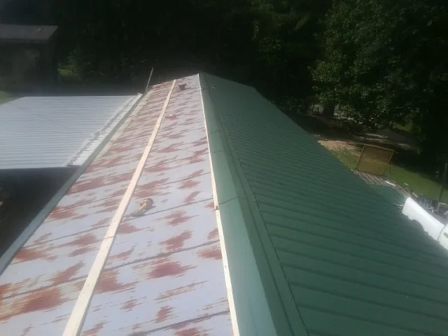 Old rusted panels beside newly installed green metal roofing — Wind Damage Roof Repair by Roofing Brothers in Illinois City