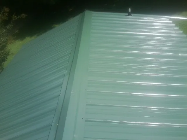 New green metal panels meeting at the ridge of a roof — Flat Roof Repair work by our crew in Illinois City