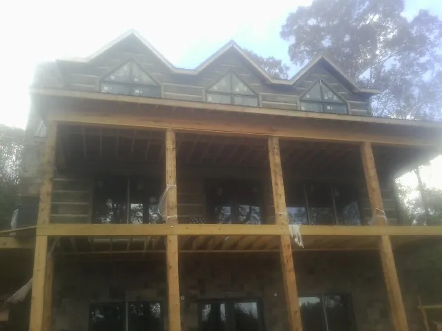 Dormers and porch framing on a large log home under construction — Roof Coating work by our crew in Illinois City