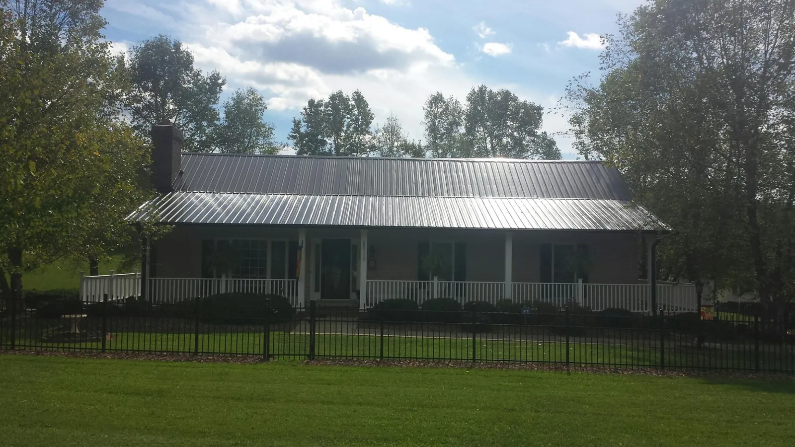 Gray metal roof on a brick ranch with a full width front porch — Gutter Guard Installation work by our crew in Illinois City