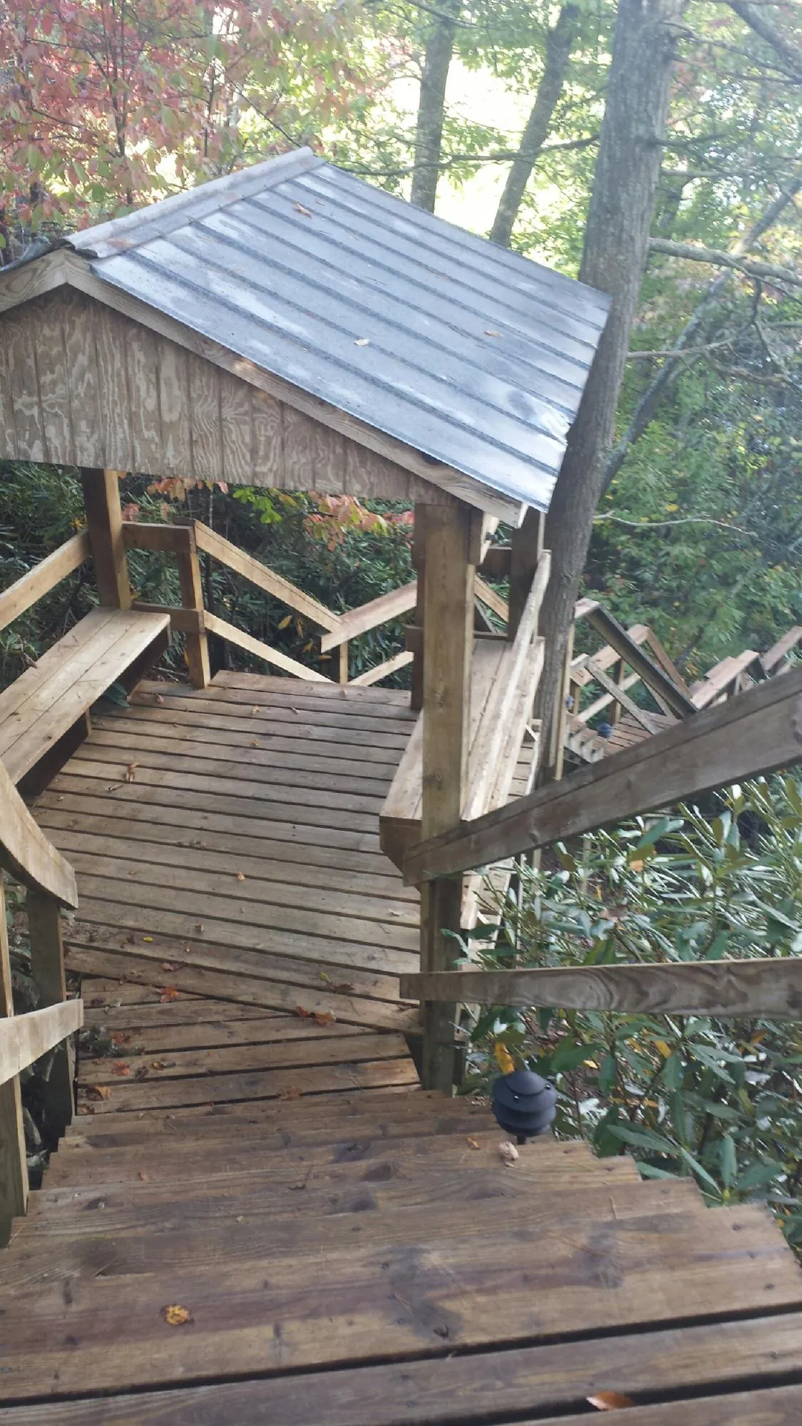 Metal roofed shelter over wooden steps on a wooded walkway — Skylight Repair & Installation work by our crew in Illinois City
