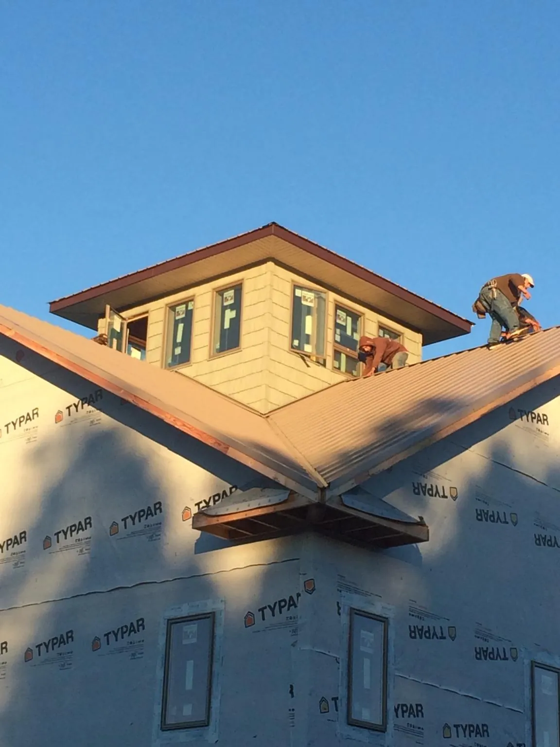 Roofers working around a rooftop cupola on a new metal roof at sunset — Roof Waterproofing in Illinois City by Roofing Brothers
